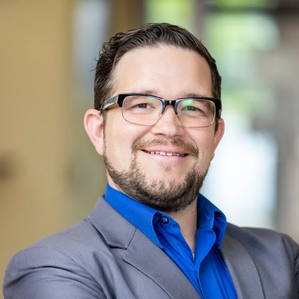 Professional headshot over a blurred background.