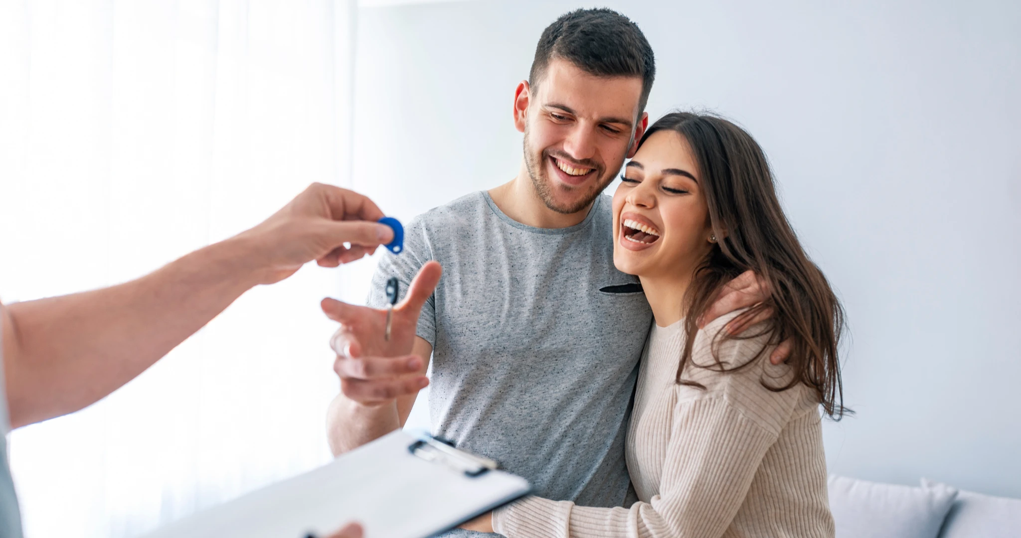 Couple smiling and grabbing keys to their new home