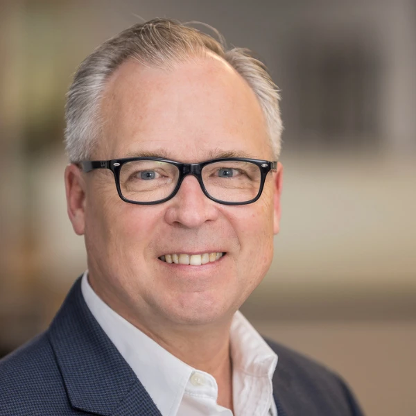 Professional headshot over a blurred background.