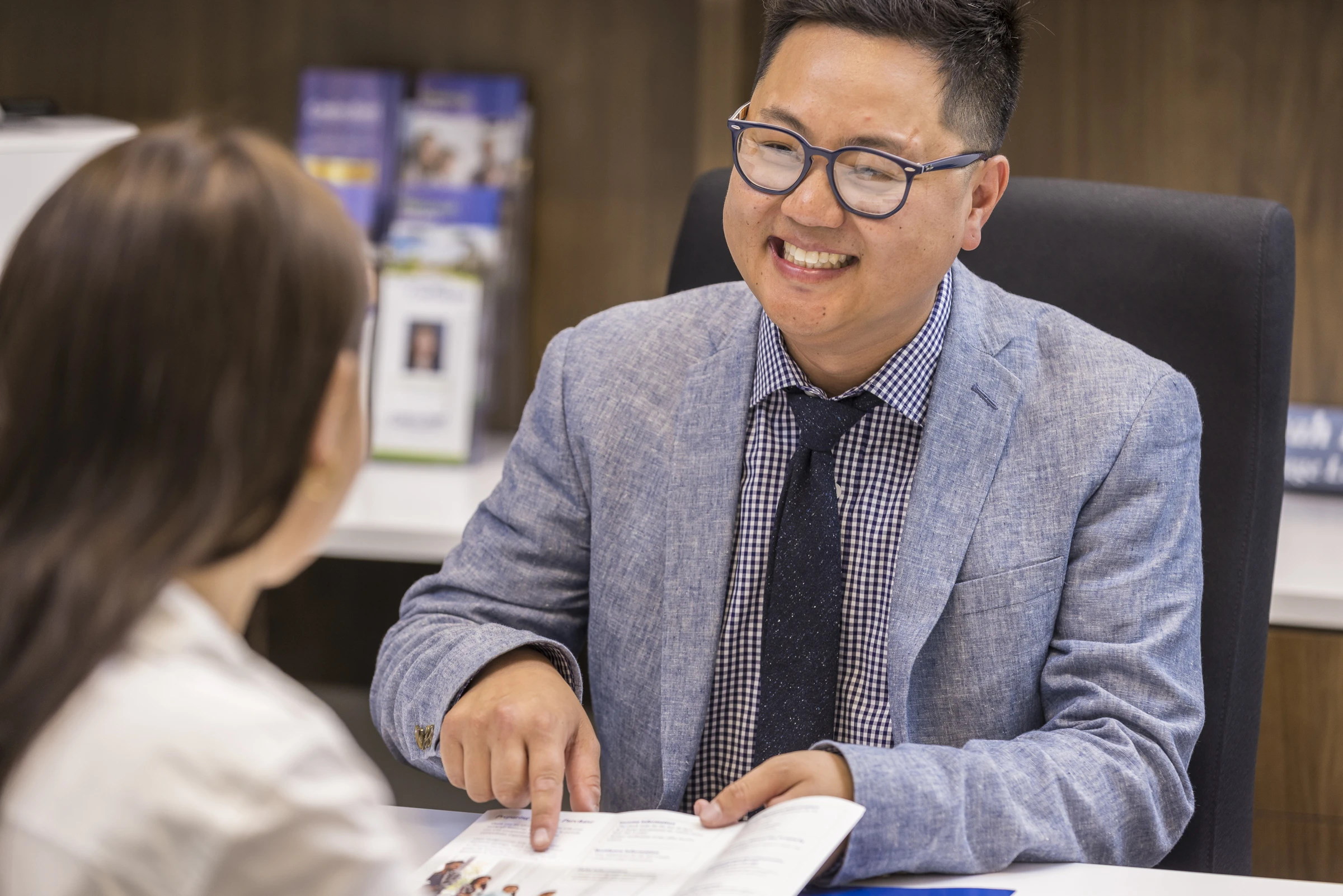 Mortgage loan officer is helping a customer at his desk and pointing at a mortgage document
