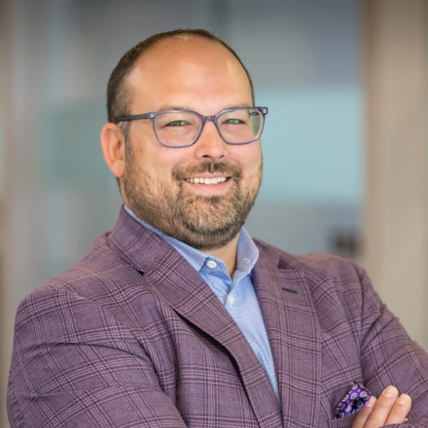 Professional headshot over a blurred background.