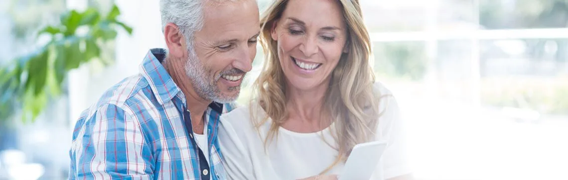 Smiling couple looking at a smartphone together.