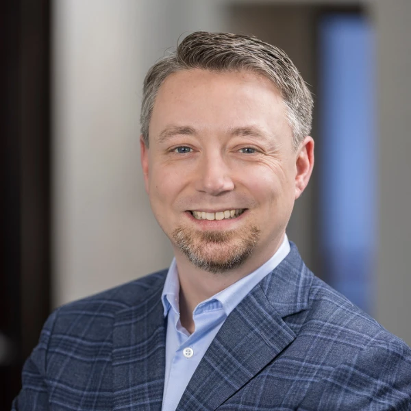 Professional headshot over a blurred background.