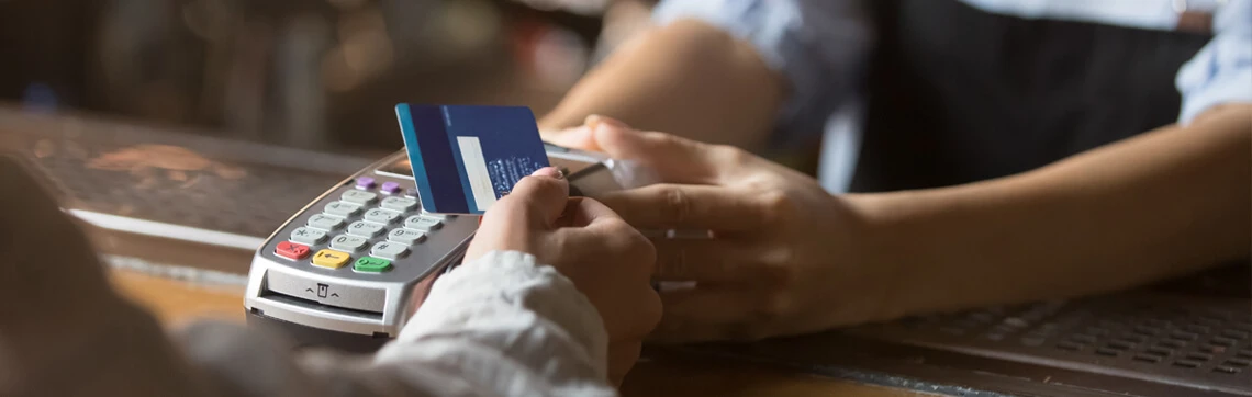 Customer making a payment by tapping a credit card on a card reader held by a cashier.