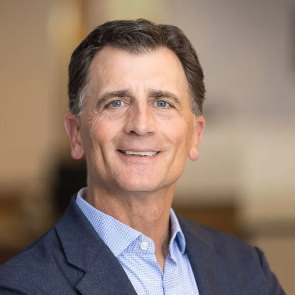 Professional headshot over a blurred background.