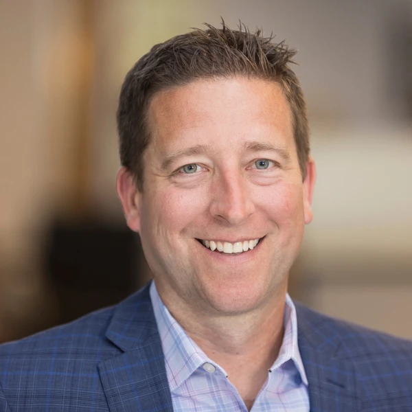 Professional headshot over a blurred background.