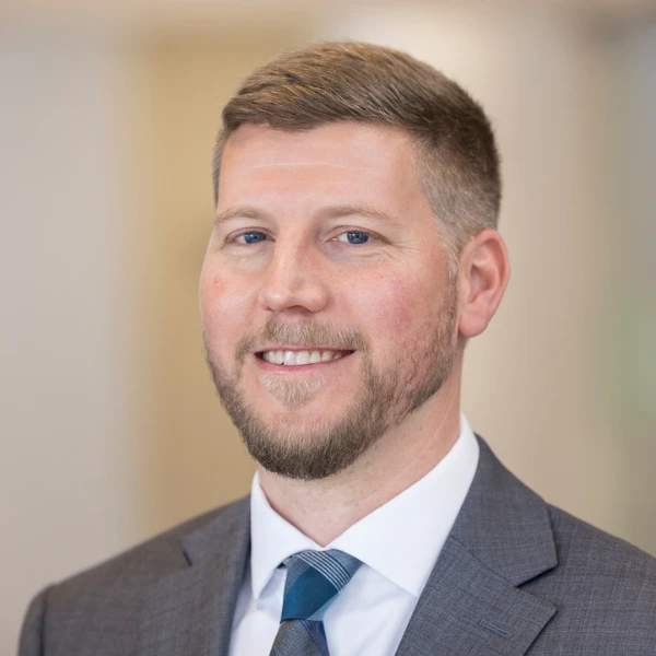 Professional headshot over a blurred background.