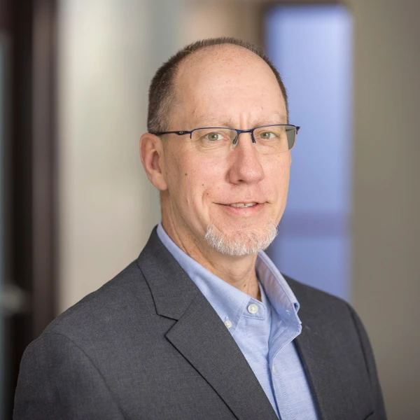 Professional headshot over a blurred background.