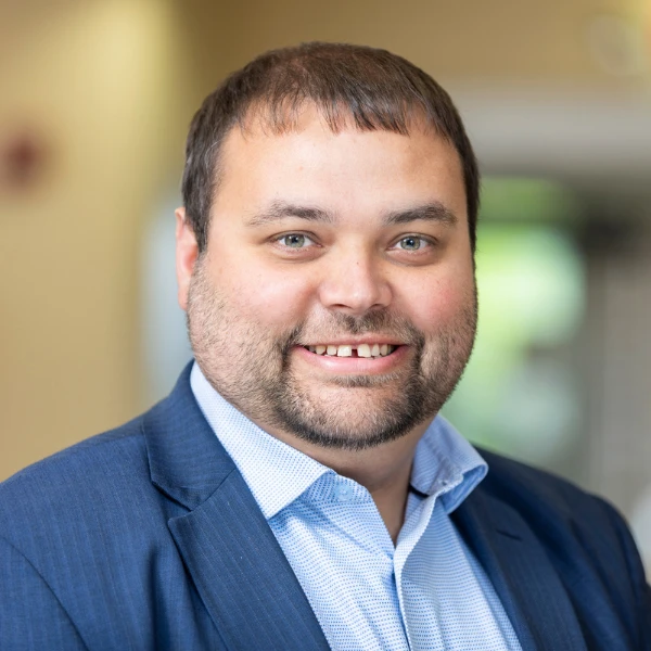 Professional headshot over a blurred background.