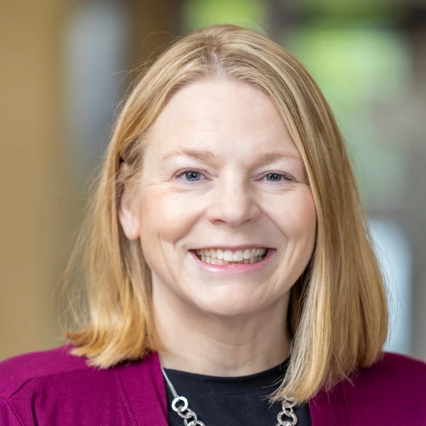 Professional headshot over a blurred background.