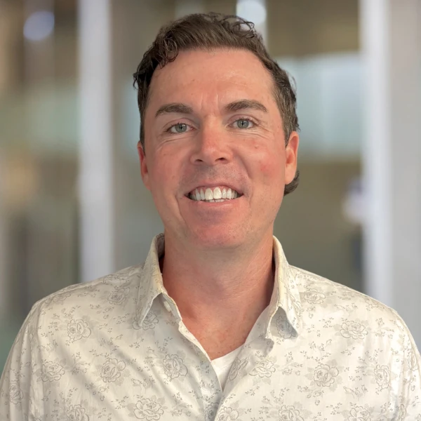 Man smiles in front of a blurred office background.