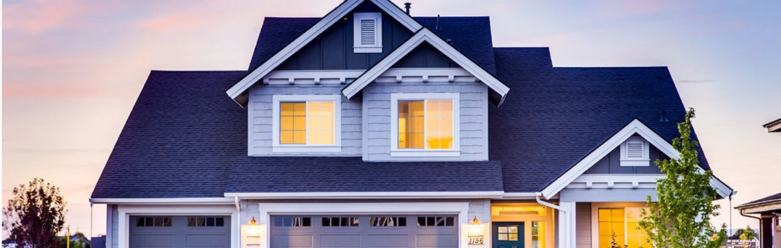 Two-story suburban house with gray siding, white trim, and a three-car garage at sunset.