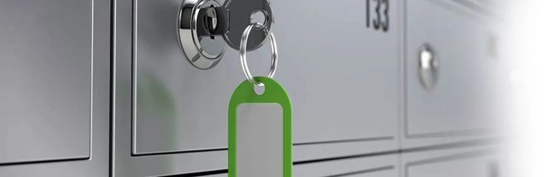 Key inserted in a silver lock of a numbered mailbox, with a green key tag attached. The image conveys security and privacy.