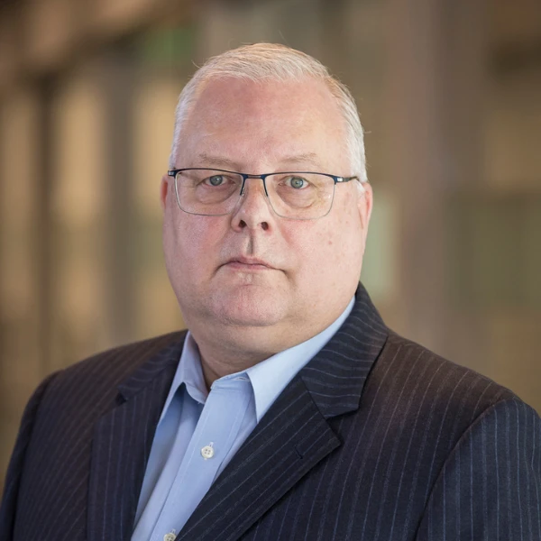 Professional headshot over a blurred background.
