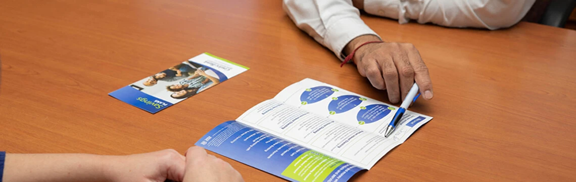 Two people reviewing a savings brochure at a desk.